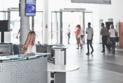 A receptionist sits behind a desk in a busy lobby of a business.